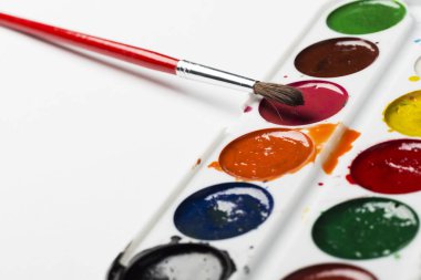 Çok renkli suluboya bir ışık gri arka plan üzerine bir fırça ile boyar. Nesneleri sanat için