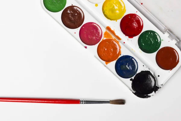 Pinturas multicolores acuarela con un pincel sobre un fondo gris claro. Objetos para el arte — Foto de Stock