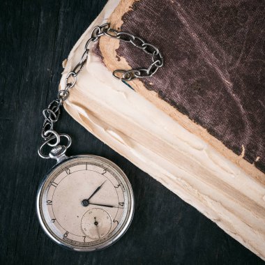 Eski püskü akıllıca kitap arka plan üzerinde çürüyen saat.