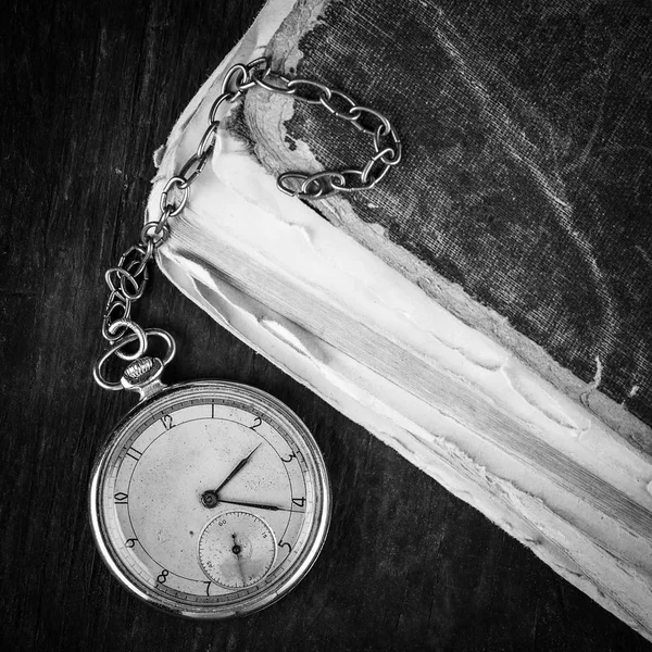 Reloj decadente en el fondo de viejos libros de mala calidad. Fotografía en blanco y negro — Foto de Stock