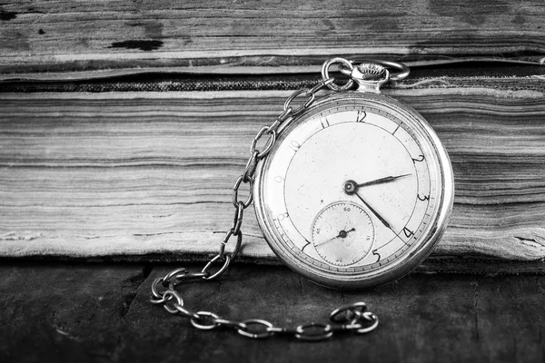 Orologio in decadenza sullo sfondo di vecchi libri squallidi saggi. Fotografia in bianco e nero — Foto Stock