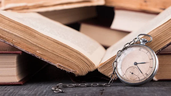 Decaying clock on the background of old shabby wise books. — Stock Photo, Image