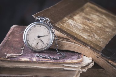 Eski püskü akıllıca kitap arka plan üzerinde çürüyen saat.