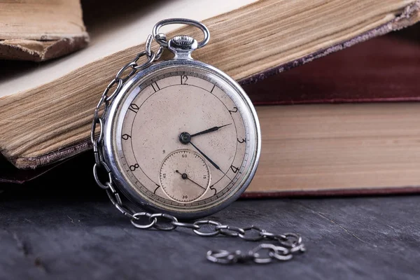 Chátrající hodiny na pozadí staré omšelé moudré knihy. — Stock fotografie