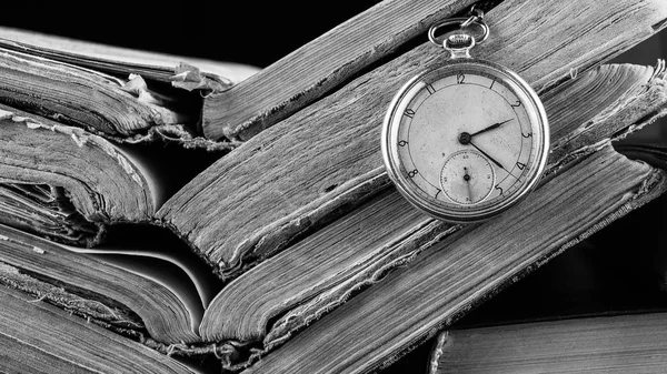 Orologio in decadenza sullo sfondo di vecchi libri squallidi saggi. Fotografia in bianco e nero — Foto Stock