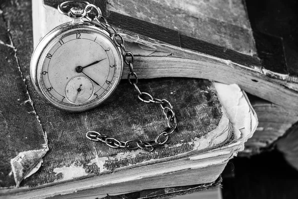 Relógio decadente no fundo de velhos livros sábios miseráveis. Fotografia em preto e branco — Fotografia de Stock