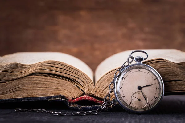 Decaying clock on the background of old shabby wise book. — Stock Photo, Image