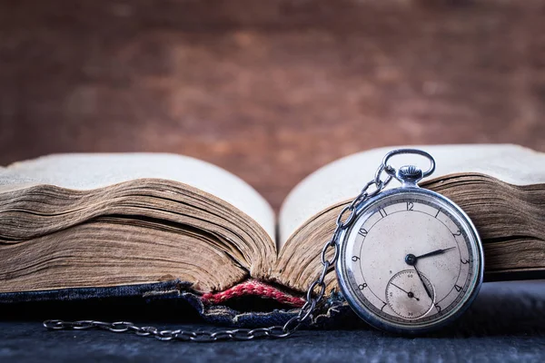 Decaying clock on the background of old shabby wise book. — Stock Photo, Image