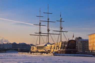 Batan güneşin ışınlarında buzla bağlanmış bir firkateyn. St. Petersburg