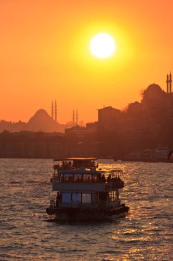 Gemi gün batımının arka planına karşı suda yelken açar. İstanbul, Türkiye