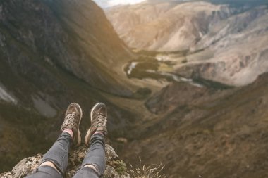 Seyahatte yüksek bir dağın tepesinde oturan gezgin bacakları. Özgürlük kavramı