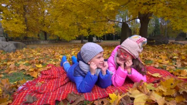 Niños en el parque amarillo de otoño. Niños pequeños y una chica de pie al aire libre en ropa brillante . — Vídeos de Stock