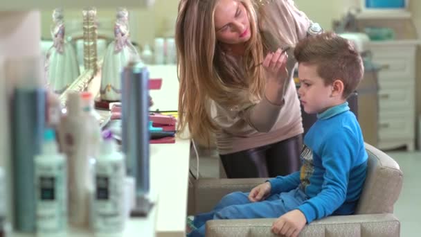 Peluquería hace que el niño estilo de pelo en el interior en el salón . — Vídeos de Stock