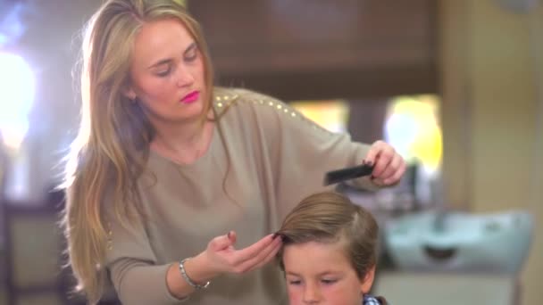 Frisören gör hår stil pojke barnet inomhus i salong. — Stockvideo