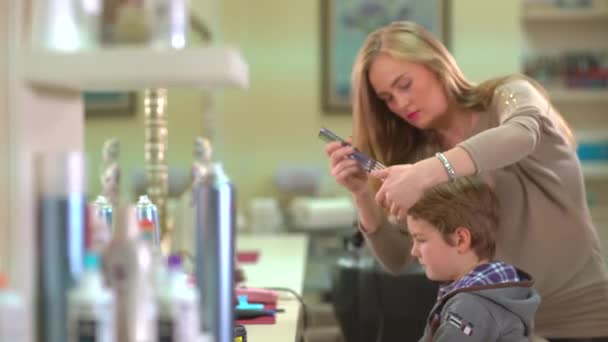 Peluquería hace que el niño estilo de pelo en el interior en el salón . — Vídeo de stock