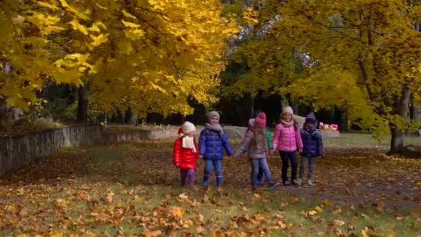 Kinder im gelben Herbstpark. Kleine Jungen und ein Mädchen stehen in heller Kleidung im Freien. — Stockvideo