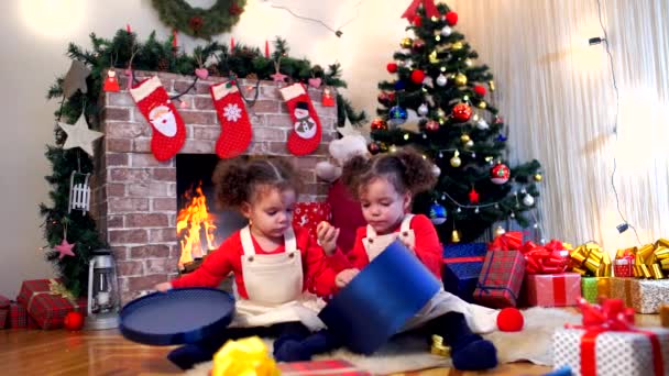 Twee kleine meisjes in caps van Santa Claus zittend op de vloer wit — Stockvideo