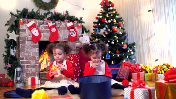 Twee kleine meisjes in caps van Santa Claus zittend op de vloer wit — Stockvideo