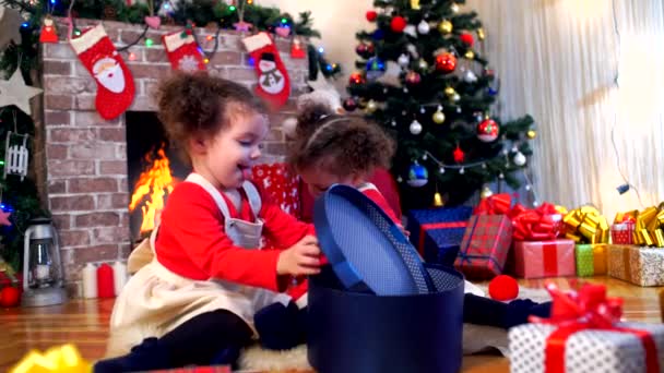 Twee kleine meisjes in caps van Santa Claus zittend op de vloer wit — Stockvideo