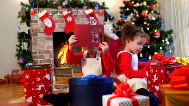 Två små flickor i caps jultomten som sitter på golvet wit — Stockvideo
