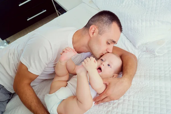 Baba ile bebek yatakta. Babası küçük öpüşme — Stok fotoğraf