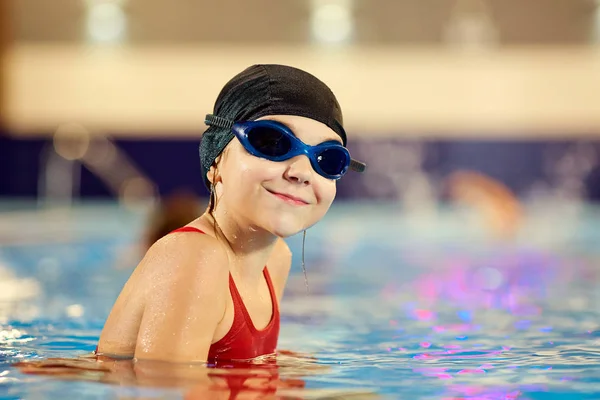 Κορίτσι παιδί κολυμβητής σε ένα κόκκινο κοστούμι λουσίματος σε φόντο — Φωτογραφία Αρχείου