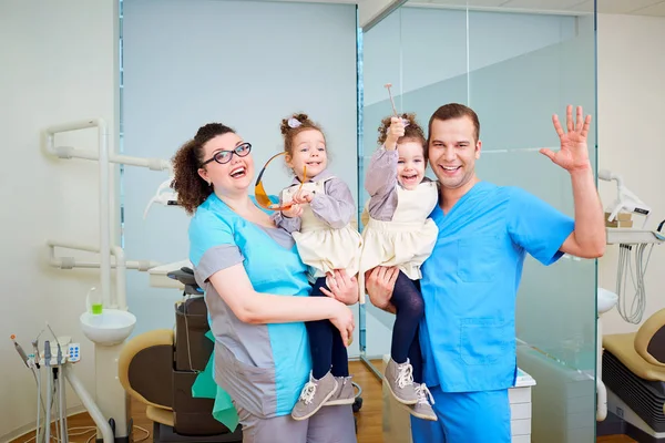 Dos dentistas con niños en sus brazos sonriendo, riendo la d —  Fotos de Stock