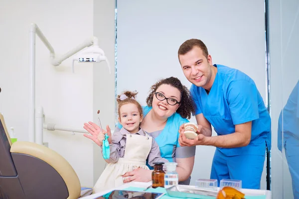 Dos clientes dentistas con un niño sonriendo en la oficina de denti —  Fotos de Stock