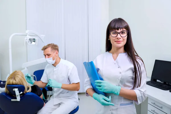 Dentiste femme dans des lunettes avec un dossier mains sur fond équiper — Photo