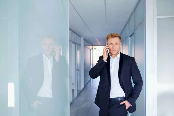 Jeune homme d'affaires blond parlant au téléphone dans un business offic — Photo