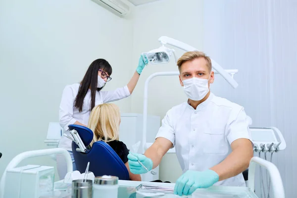 Człowiek dentysta z asystentem leczy zęby pacjenta w szpitalu ofi — Zdjęcie stockowe