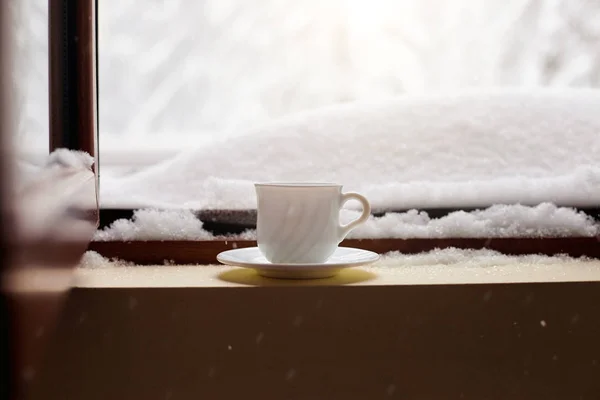 Mug with tea and coffee on the window sill snow in winter w