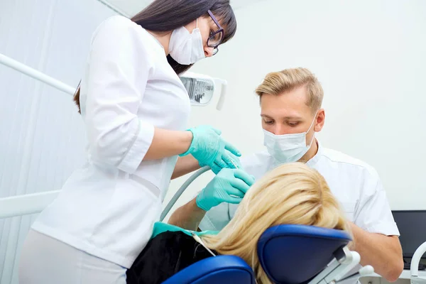 Dentiste homme avec assistant traite les dents patient à l'hôpital offi — Photo