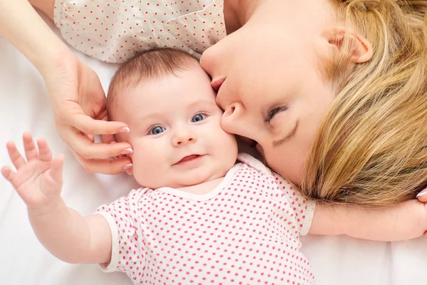 Mum kisses baby on the bed — Stock Photo, Image