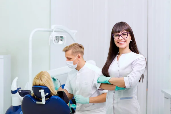 Dentiste femme dans des lunettes souriant sur l'équipement de fond — Photo