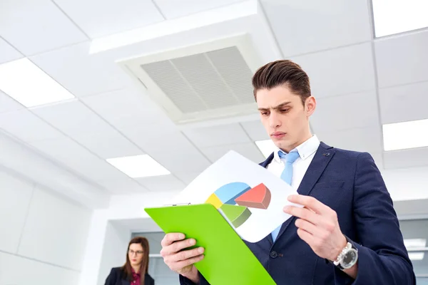 Empresário olhando para o documento, em gráfico de escritório — Fotografia de Stock