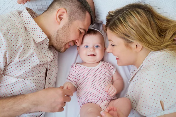 Familia feliz. Padres con bebé en la cama. Primer plano. — Foto de Stock