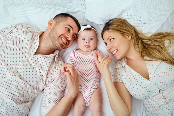 Madre y padre felices sonriendo con su bebé acostado en la cama. Papá. — Foto de Stock