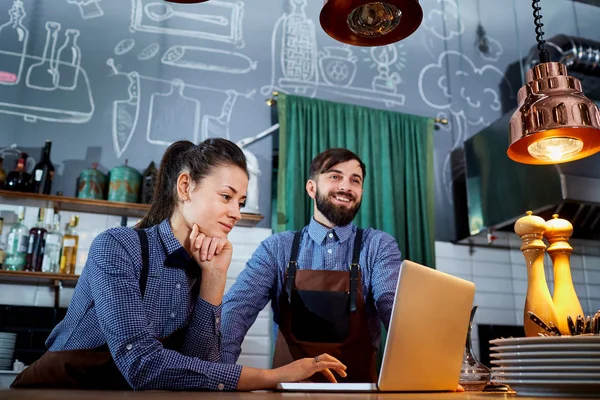 La camarera barista mujer con un portátil en el trabajo en el restaurante — Foto de Stock