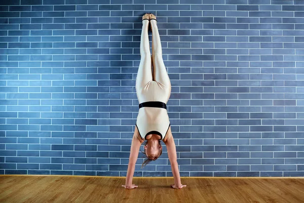 Girl athlete in headstand near brick wall the gym. A woman doing — Stock Photo, Image