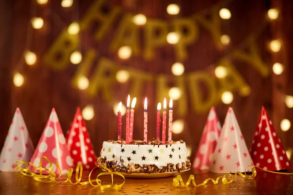 Feliz bolo de aniversário com velas no fundo de guirlandas um — Fotografia de Stock