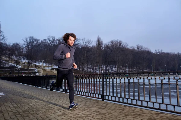 Joven hombre rizado corriendo en el parque la tarde de primavera — Foto de Stock