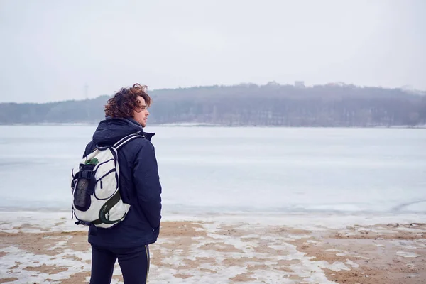 Kudrnaté vlasy muž v saku s batoh zima na jezeře jezdí — Stock fotografie