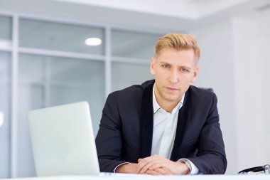 Ofiste bir dizüstü bilgisayar ile onun masasında çalışan iş adamı