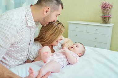 Annem ve babam yatağa bebekle oynarken. Mutlu bir aile