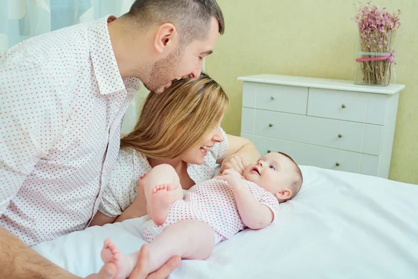 Annem ve babam yatağa bebekle oynarken. Mutlu bir aile — Stok fotoğraf