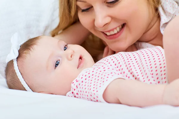 Mère jouant avec son bébé sur le lit. Maman sourit à son enfant — Photo