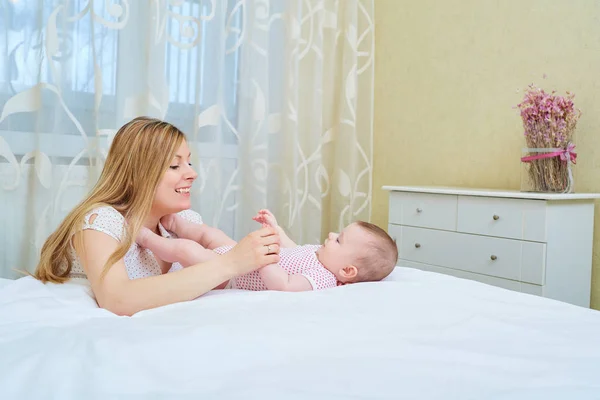 Matka, hrát se svým dítětem na postel. Usmívá se maminka své dítě — Stock fotografie