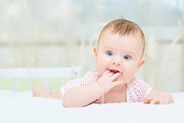 Criança infantil engraçada com olhos azuis deitada na cama — Fotografia de Stock