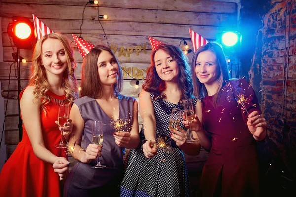 Meninas para a festa de aniversário nos bonés em suas cabeças e com sparklers suas mãos — Fotografia de Stock